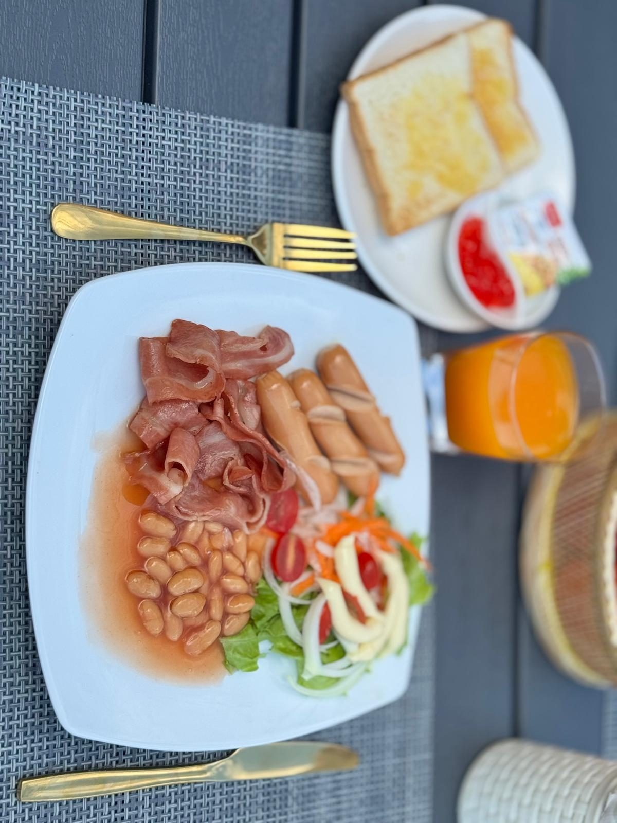 Cooked breakfast — bacon, sausages, beans and salad, with toast and orange juice