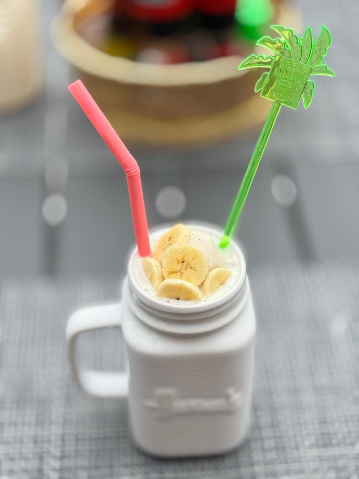 Banana smoothie in a glass jar, topped with sliced banana
